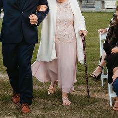 a man and woman walking down the aisle at an outdoor ceremony with their canes in hand