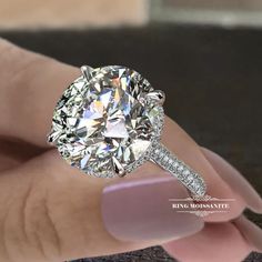 a close up of a person's hand holding a diamond ring