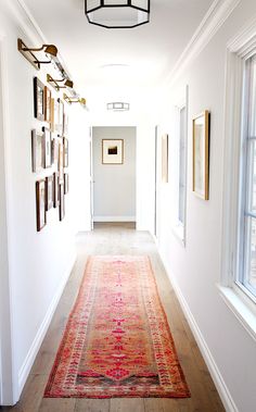 Hallway with white walls, framed artwork, wood floors, and bright patterned rug Renovation House, Best White Paint, Hal Decor, Long Hallway, White Paint Colors, Narrow Hallway, Vintage Interior, Style At Home, Cozy Cottage