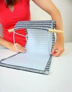 a woman is holding a piece of paper and threading it to the top of her binder