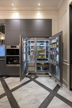 a stainless steel refrigerator and freezer combo in a large kitchen with marble flooring