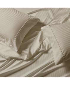 an unmade bed with white sheets and pillows on it's side, close up