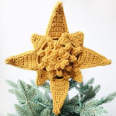 a crocheted star ornament on top of a pine tree with needles