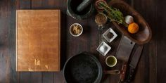 a wooden table topped with lots of different types of cooking utensils and food