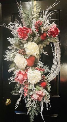 a wreath with red and white flowers hanging from it's side on a door