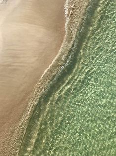 an aerial view of the ocean and beach with waves coming in from the water,