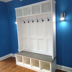 an empty room with blue walls and white shelves on the wall, along with wooden flooring