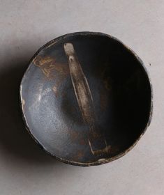 an old black bowl sitting on top of a white counter next to a wooden spoon