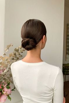 a woman with her back to the camera, wearing a white top and holding a bouquet of flowers