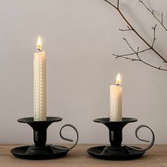 two white candles sitting on top of black candle holders