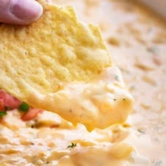 a tortilla chip being dipped with cheese and salsa