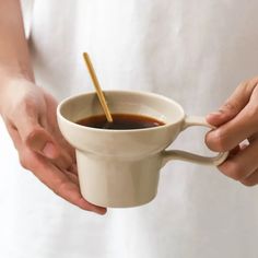 a person holding a coffee cup with a spoon in it