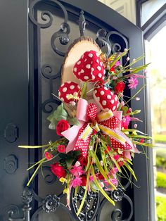 a red and white polka dot wreath on a black door with pink flowers in it