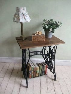 an old sewing machine and some books on a small table with a lamp next to it