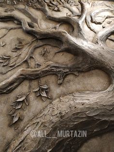 an intricately carved tree branch on the side of a stone wall with vines and leaves