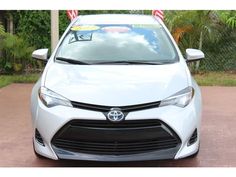 a white toyota car with an american flag sticker on it's windshield is parked in a driveway