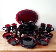 a collection of red and black dishes on a wooden table