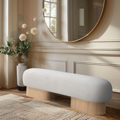 a white bench sitting in front of a round mirror