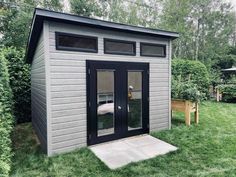 a small gray shed sitting on top of a lush green field