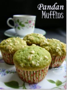 three green muffins sitting on top of a plate next to a cup