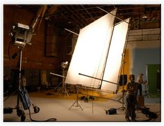 two people standing in front of a large white object on a tripod with lighting equipment around it