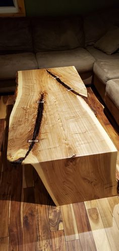 a wooden table sitting on top of a hard wood floor next to a white couch