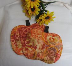 three decorative pumpkins sitting on top of a white table cloth with sunflowers in the background