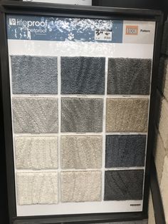 a display case with various colors of carpet for sale on the floor in front of a brick wall