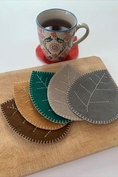 four coasters sitting on top of a cutting board next to a cup of coffee