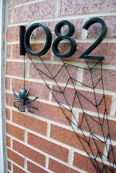 a house number sign on the side of a brick building with spider webs attached to it