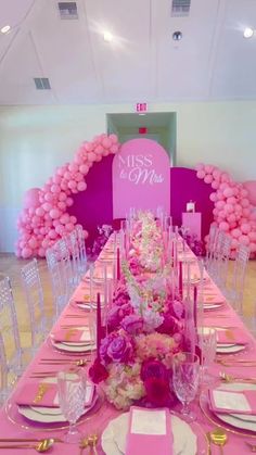 a table set up with pink and white flowers, balloons and candles for a wedding reception