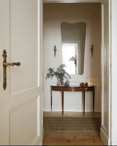 an entry way with a mirror and table in it