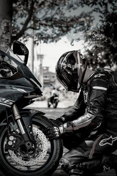 a man sitting on the back of a motorcycle next to another person wearing a helmet