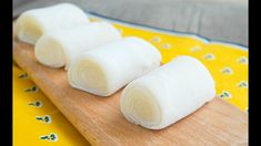 three rolls of white cotton sitting on top of a wooden cutting board