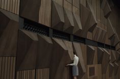 a person standing in front of a wooden wall with geometric designs on the outside and inside