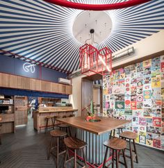 the inside of a restaurant with lots of wooden stools and colorful wallpaper on the walls