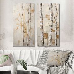 two paintings are hanging on the wall above a white couch in a living room with a coffee table