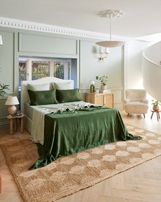 a bedroom with green bedding and white walls, wooden floors and an area rug on the floor