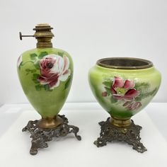 two green vases with flowers painted on them