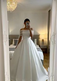 a woman in a white wedding dress taking a selfie