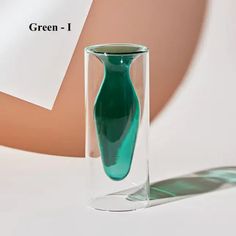 a green vase sitting on top of a white table