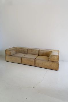 a tan leather couch sitting on top of a white floor in front of a wall