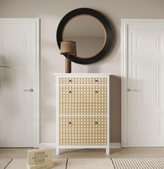 a white and gold dresser with a round mirror on the wall next to an open door