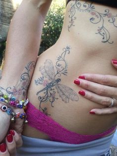 a woman with tattoos on her stomach holding onto another woman's belly and wearing bracelets