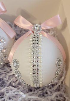 an ornament in the shape of a ball with pearls and bows on it