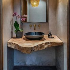 a bathroom sink sitting under a mirror on top of a wooden counter next to a potted plant