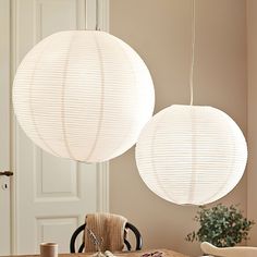 two white paper lanterns hanging over a dining room table