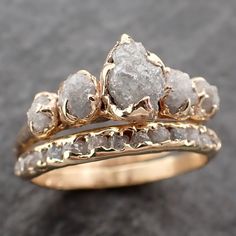 two gold wedding rings with rough white diamonds on each one, set against a black background