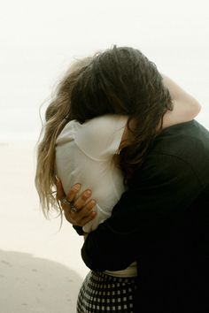 a woman hugging her face on the beach