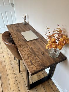 a wooden table with two chairs next to it and a vase filled with flowers on top